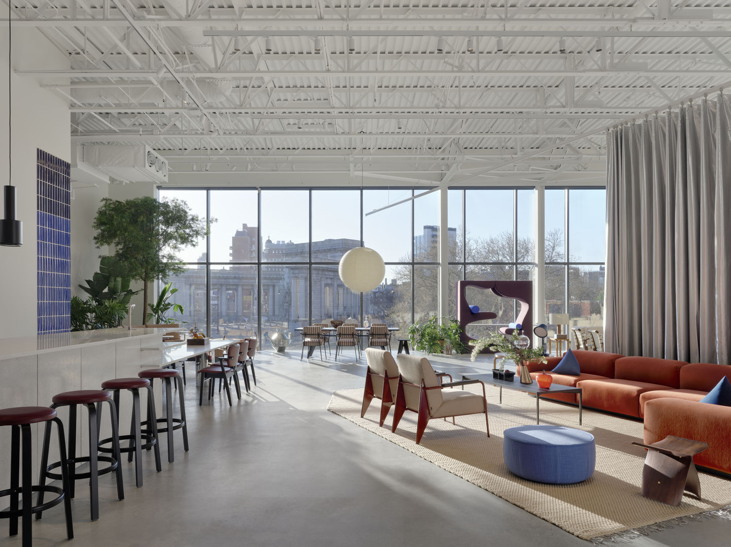 Loft showroom with a bar counter, a lounge zone, and a communal meeting table